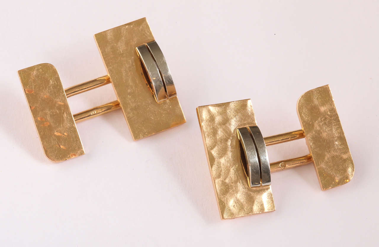 The martele base in yellow gold has applied to it a convex double bar in white gold attached by an oval ring to the small side with martele surface and square corners alternating with round corners.

Hallmarked for 18 kt gold with eagle’s head/