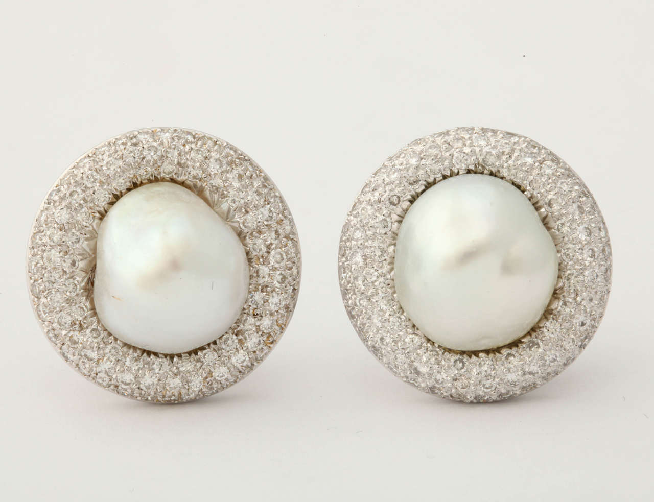 One Pair Of Gorgeous 18kt White Gold Clip On Earrings With Posts NOTE: Posts May Be Removed If Not Needed. Earrings Are Embellished With 2 {12} MM Large High Lustre Baroque Pearls in Center & Surrounded by Approximately 4 Carats Of Full Cut