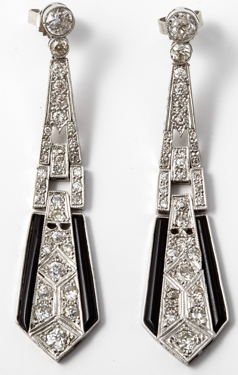 Ein Paar Art-Déco-Onyx- und Diamant-Anhänger-Ohrringe, besetzt mit Diamanten im Zwischenbrillant- und Schweizer Schliff. Beide Seiten der Ohrringe enden mit langen, schmalen, konisch geschliffenen Onyxsteinen. Das Gesamtgewicht der Diamanten wird