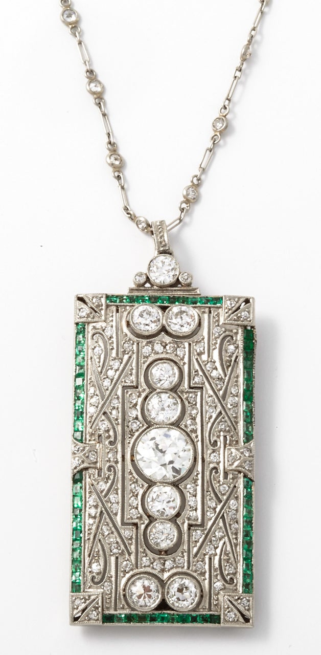 An exemplary Art Déco diamond and emerald brooche/pendant. In the center is a large intermediate brilliant cut diamond of circa 1.25 ct, colour H-I and clarity VS2/Si1. On either side are 8 primary diamonds with a total weight of 1.50 ct with a