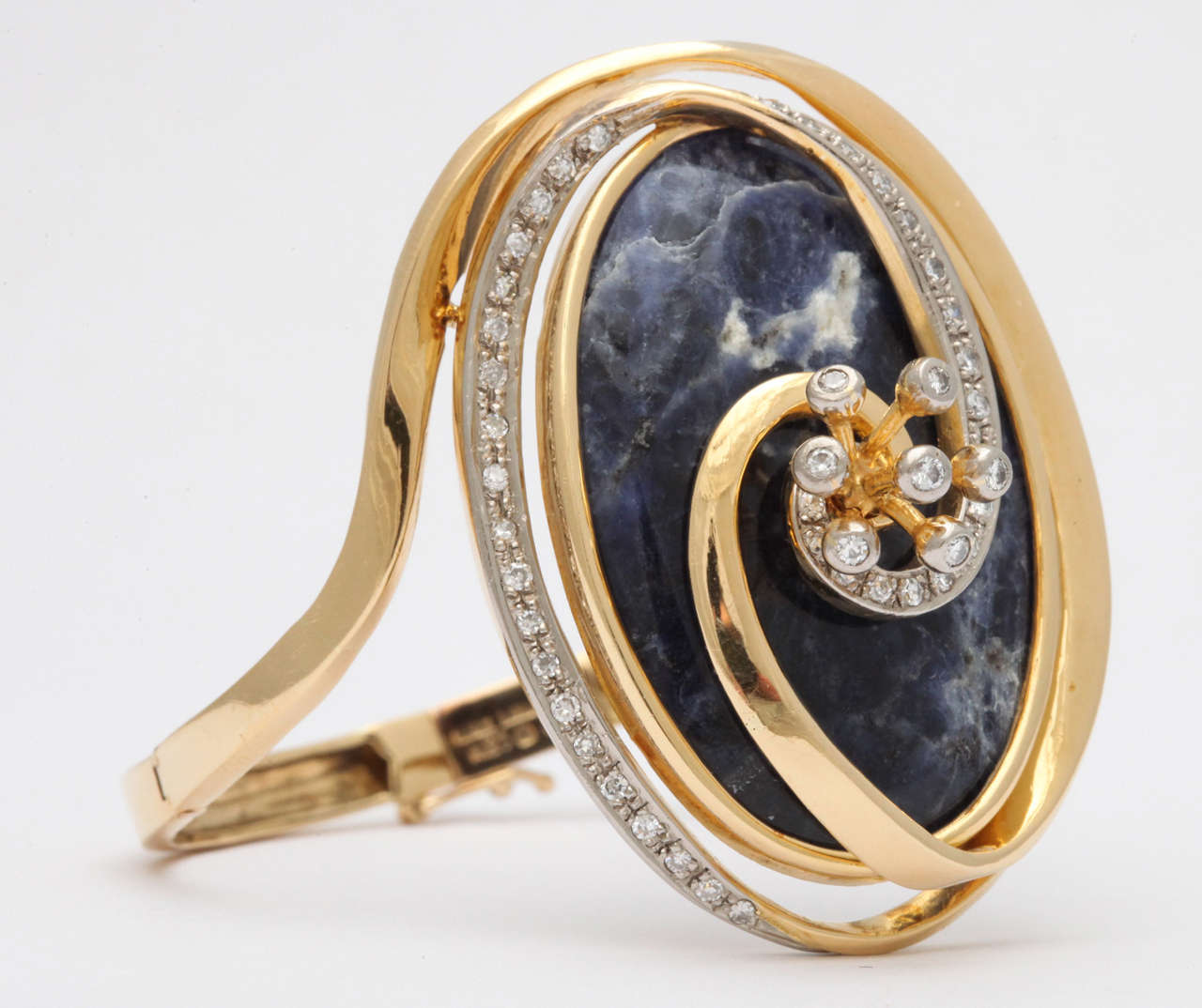 18kt Yellow Gold swirl shaped Bracelet  set with Diamonds on a Sodalite Base & centered with a spray of Diamonds.  Hinged on either side and partially encircled by a swirl of Diamonds  Matching Ring available