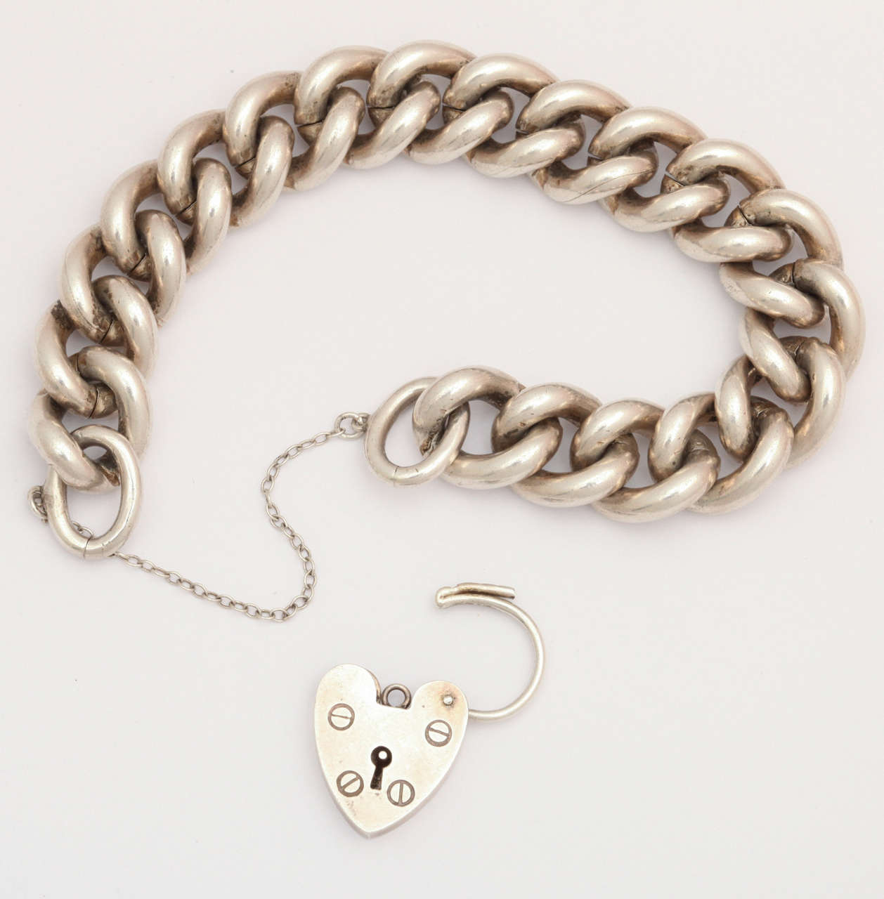 A solid silver curb link bracelet from Birmingham, England holds a padlock clasp in the form of a heart.  The bracelet, heavier than most of its kind, is sturdy enough for a man and handsome aplenty for a lady. The curb link form is tactile, feels