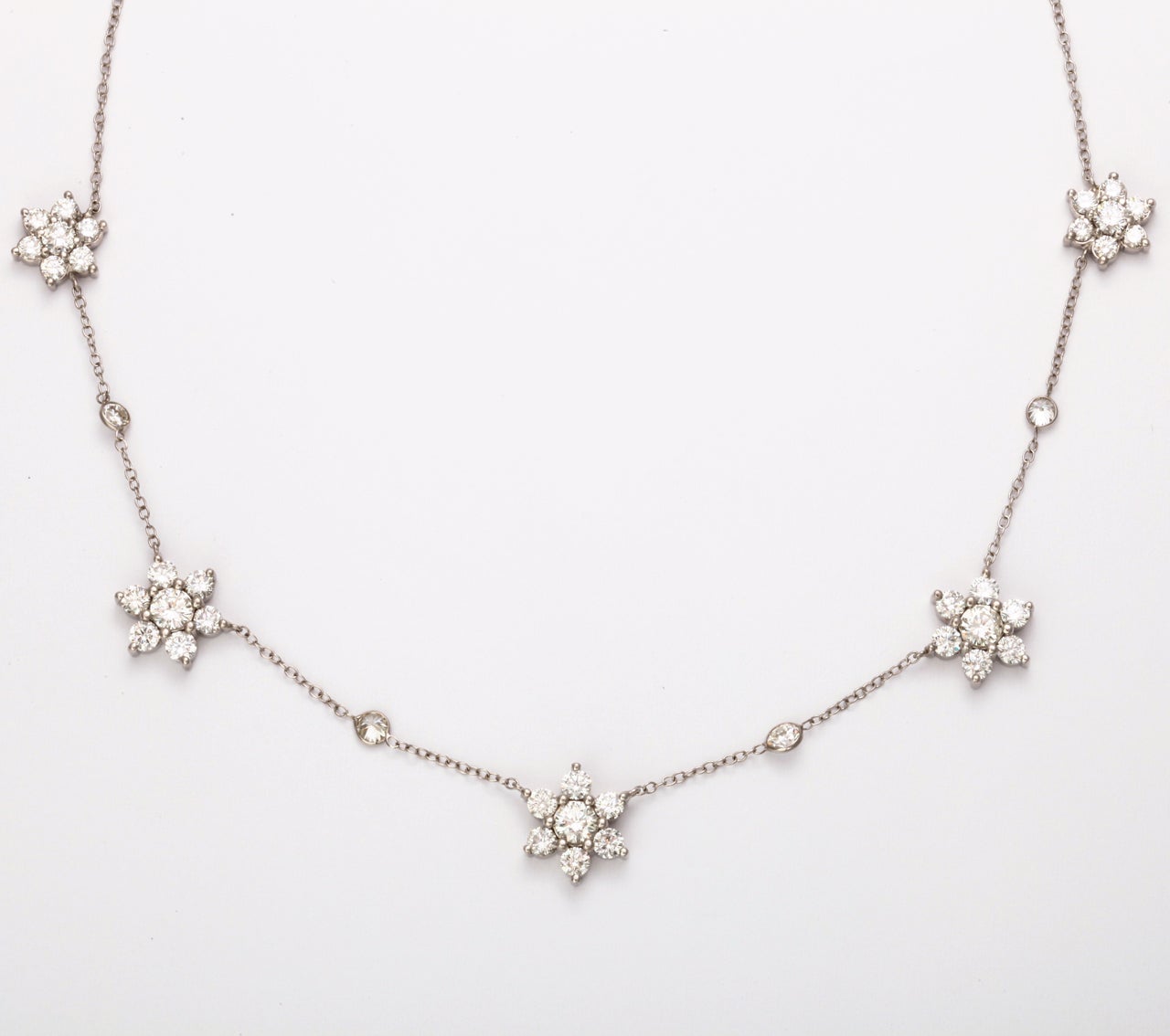 A MUST HAVE....this diamond flower cluster necklace features three large clusters weighing 2.50 atw, two medium clusters on each end, weighing 1.50 atw, on a white gold diamond by the yard, 0.60 atw. 

Can custom make this necklace for you!