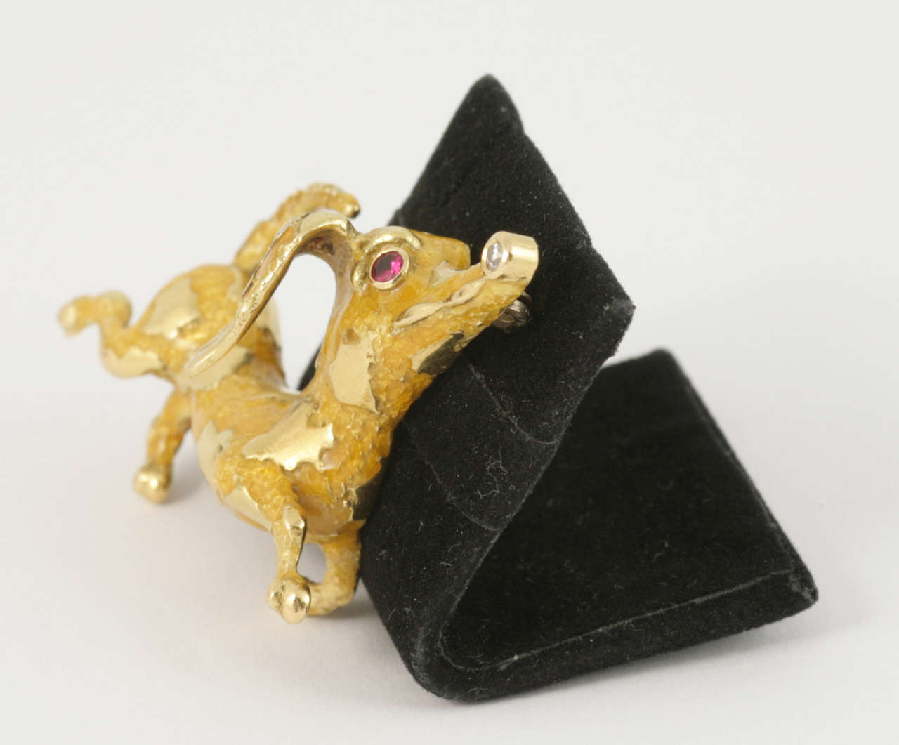 A cheeky dachshund brooch by Frascarolo. 
The sausage dog has a 18 carat yellow gold body with yellow enamel on it. 
The eye is ruby set and the nose and ear are diamond set.