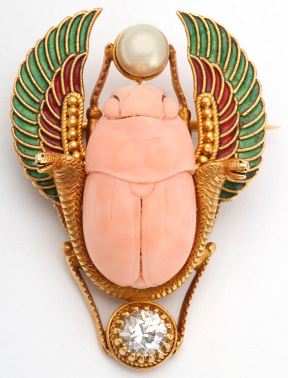 egyptian revival scarab brooch with angel skin coral scarab bug carving with superior quality old european cut diamond and plique ajour red and green enamel for wings wih natural pearl on top of brooch mounted on 18kt yellow gold