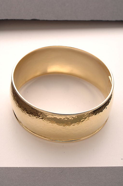 Hammered eighteen karat gold bangle bracelet by Ippolita. Inside diameter is 2 7/16"; height is 15/16". Excellent condition.