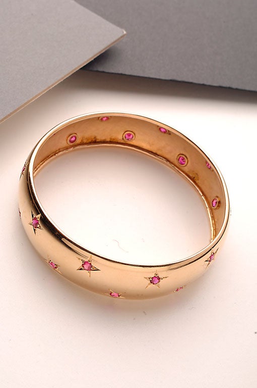 Tested fourteen karat gold bangle bracelet with rubies. Stones are set within a five point star as is typical of the 1940's. Measures 5/8