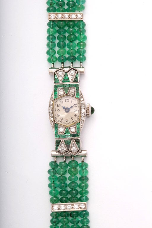 Perfect for evening attire, this elegant Art Deco diamond & emerald Longines platinum watch was later fitted with a custom band.  The band has diamond spacers and a clasp with an emerald cabochon all set in 14k white gold. The rest of the band is