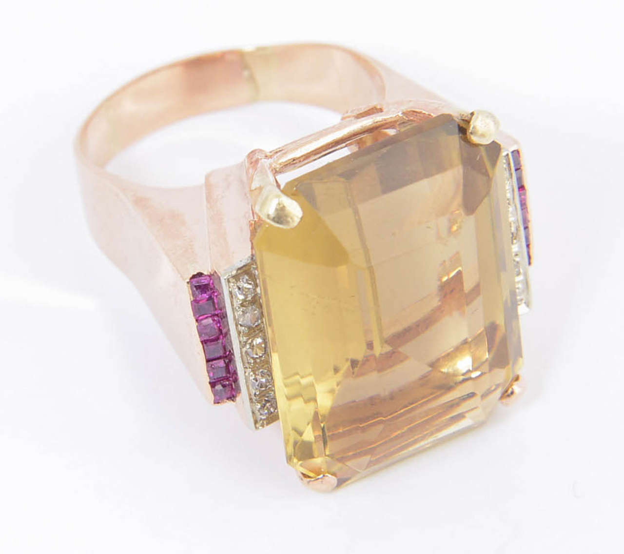 Perfect example of a 1940s cocktail ring.  It even has the synthetic rubies that were widely used during the Retro Era.  Large emerald cut citrine accented with prong set diamonds and channel set synthetic rubies.  The mounting is 18k rose gold.
US