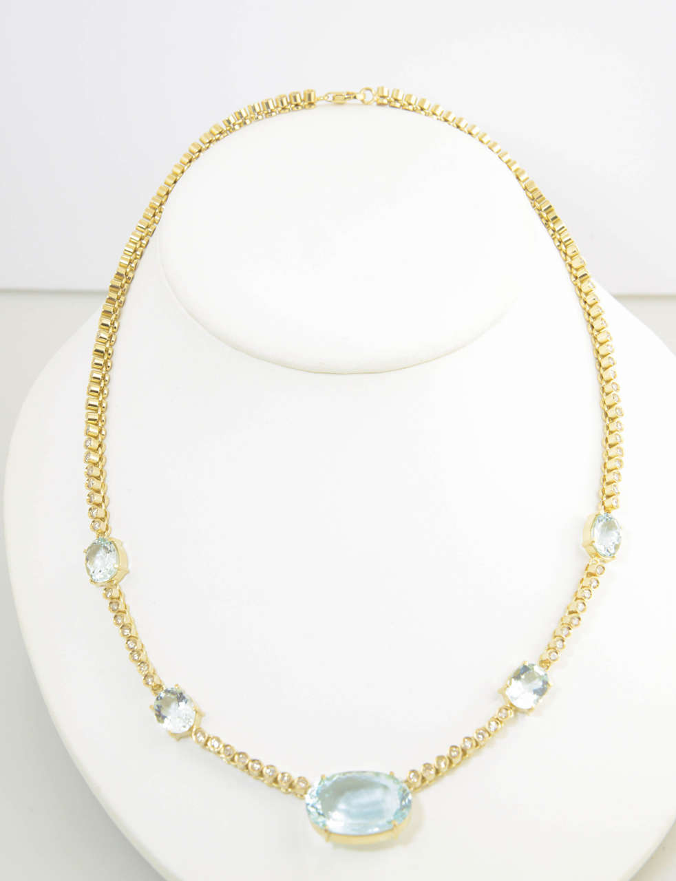 Necklace features bezel set diamonds and 5 prong set aquamarines set in 18k gold. The largest aqua is 3/4