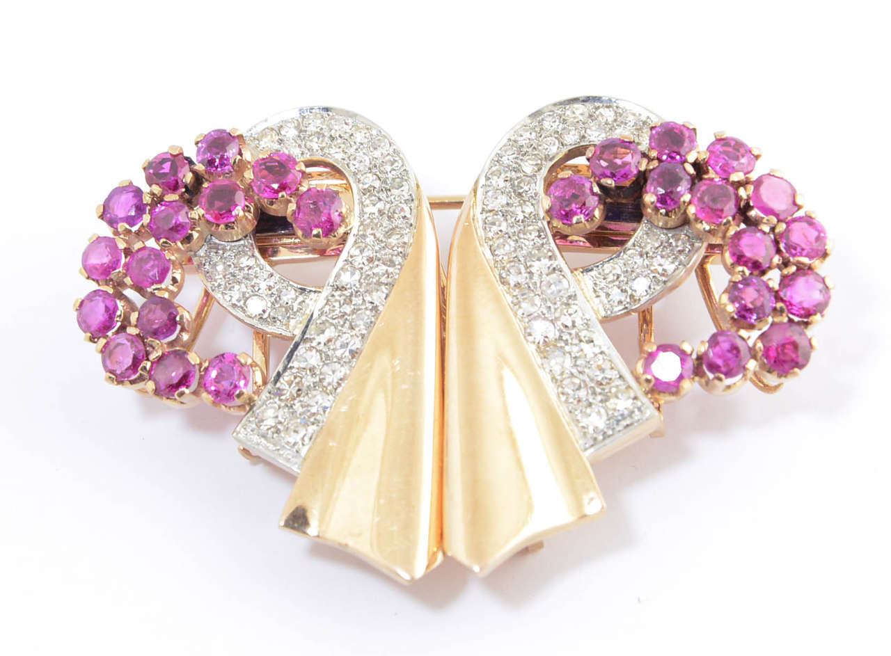 This beautiful 1940's clips  can be worn separately or together by its custom fitting.   The diamond and gold ribbon swirl in accented with prong set rubies. The brooch and fitting are 18k rose / pink gold.   The approximate diamond weight is 1.55