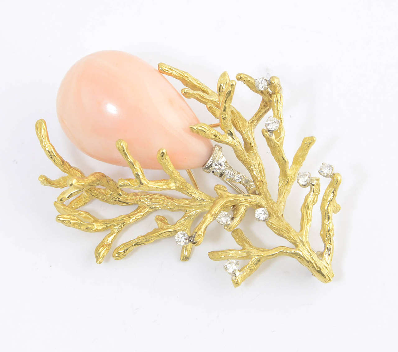 Features a large teardrop piece of coral set in a typical 1960's 18k yellow gold bark mounting with diamond accents.