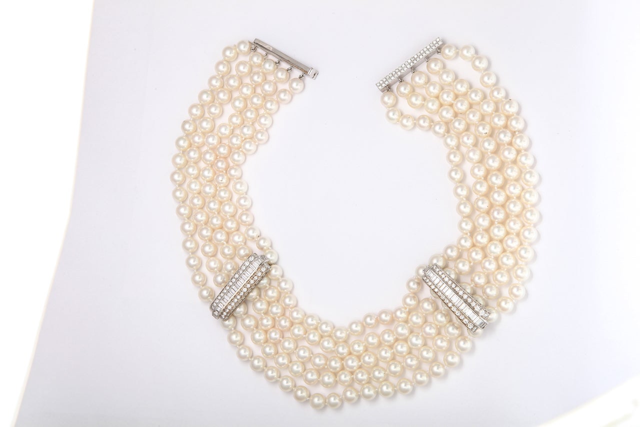 A stunning 5 row pearl necklace with 2 white gold bars that is contained with brilliant and baguette cut diamonds as well as a clasp which contains brilliant round stones. The diamonds weigh approximately 20.75 cts. The pearls are cultured and has a