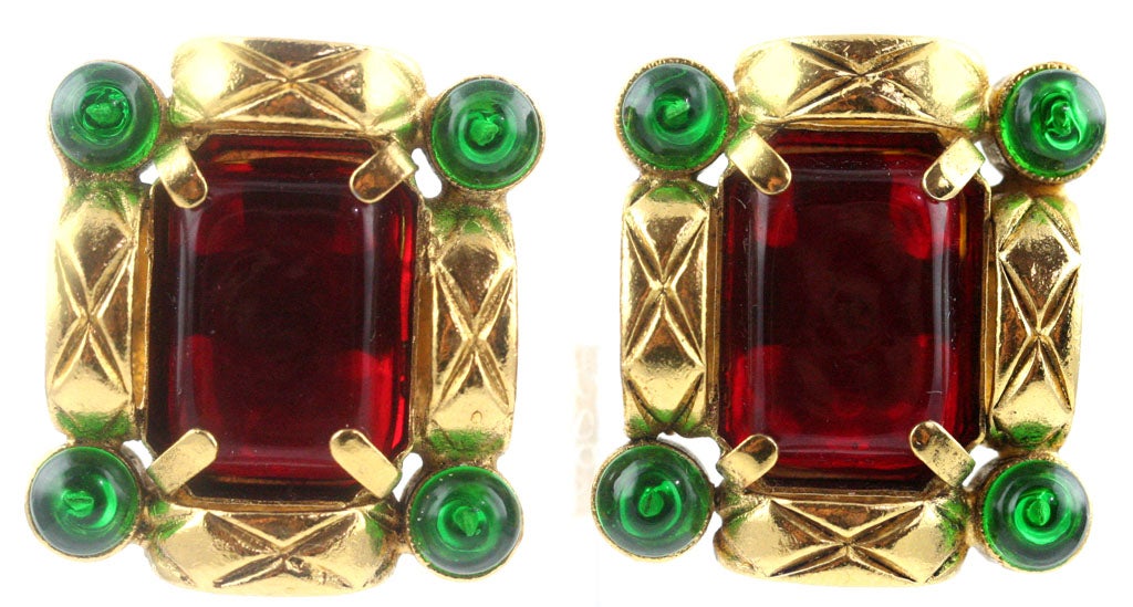 A chic pair of Chanel ear clips with ruby and emerald poured glass set in gilt metal stamped with a quilted design. The oval cartouche signature plate on the back is stamped 