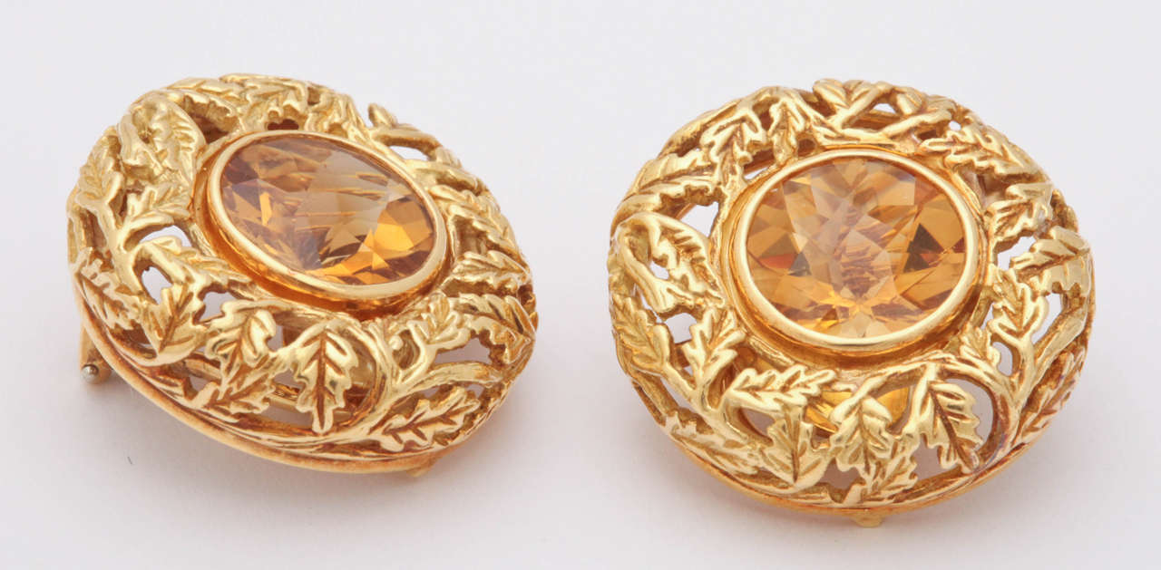 These day or night  earrings are made of a carved lacy leaf pattern in 18 kt gold.. Bold in size but delicate in apperance. The leaves surround a .5 in round checkerboard cut citrine with a beautiful sparkle. There is a large omega clip in the back