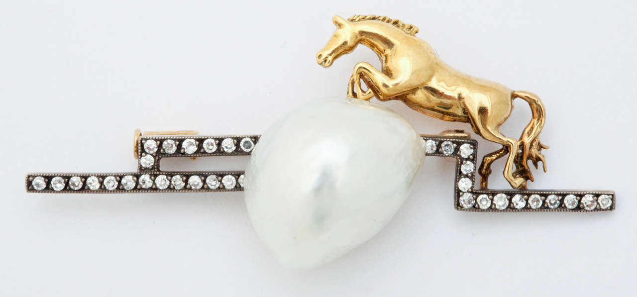 18k gold horse jumping over a baroque South Sea pearl. The diamonds are set in silver for an estate look. This brooch makes a great lapel or stock pin.