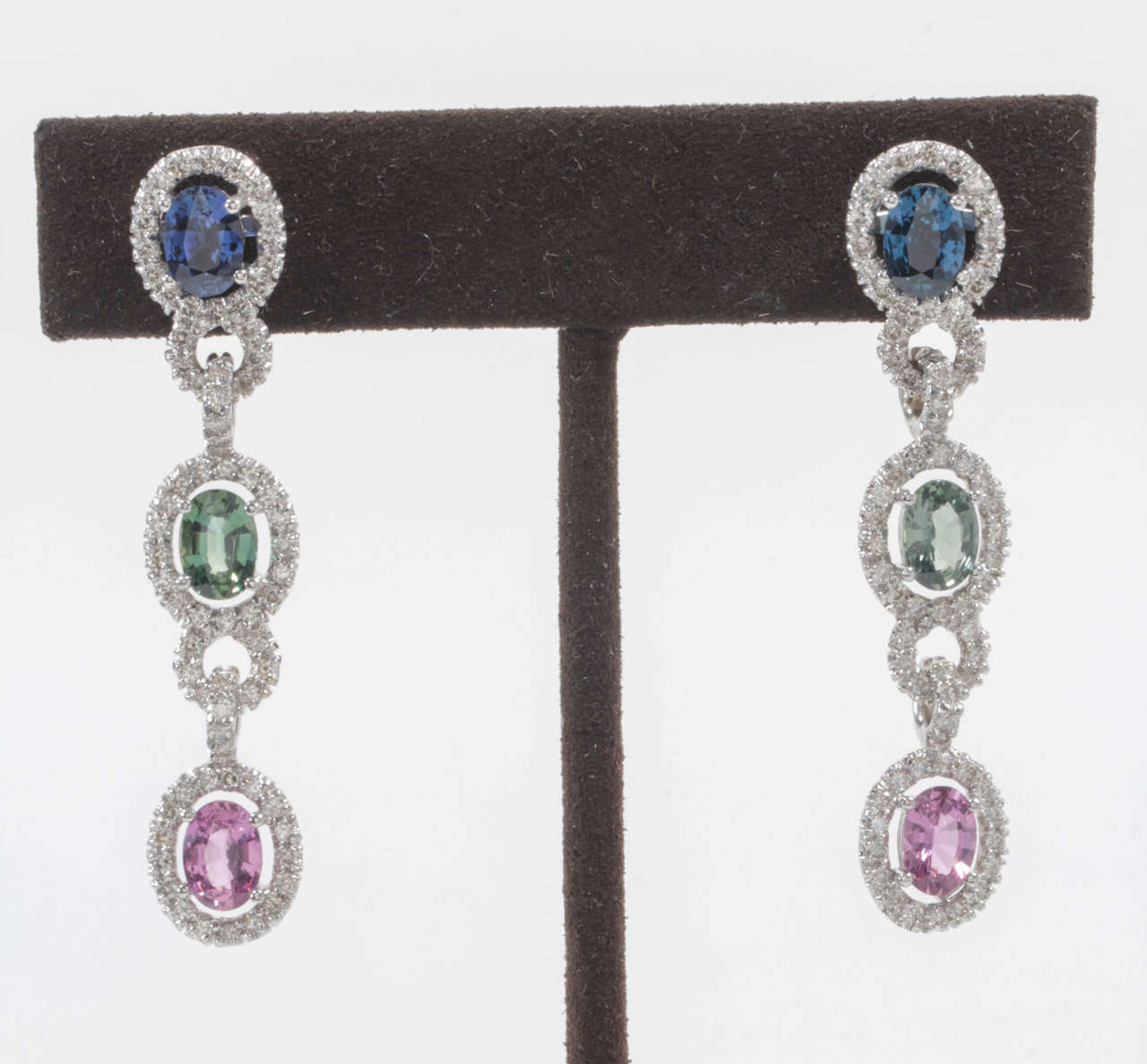 7.26 carats of blue/violet, green and pink sapphires set with 3.52 carats of round brilliant cut diamonds. 

Approximately 2 inches in length.

All set in 18k white gold