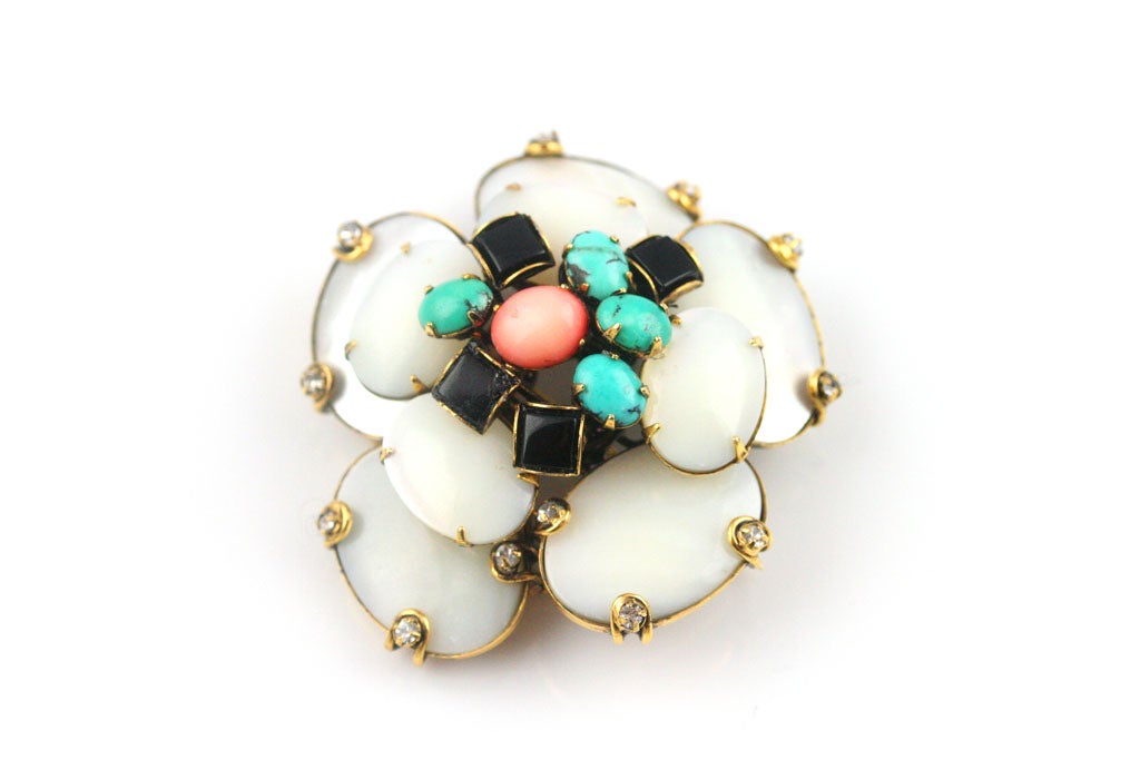 A beautiful flower brooch by Iradj Moini composed of mother of pearl, onyx, turquoise, coral and rhinestones set in gilt metal.