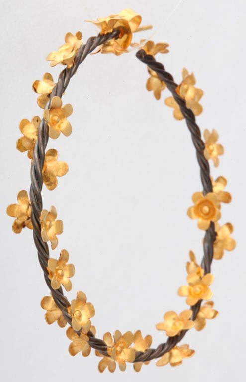 A pair of rhodium plated sterling silver rope hoop earrings which have been decorated with 18kt yellow gold flowers.