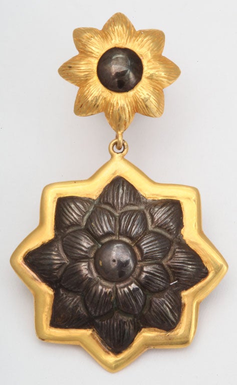 A pair of earrings composed of rhodium plated sterling silver sunflowers which have been bordered by 18kt yellow gold borders and are suspended from 18kt yellow gold sunflower studs which have been bordered by rhodium plated sterling silver.