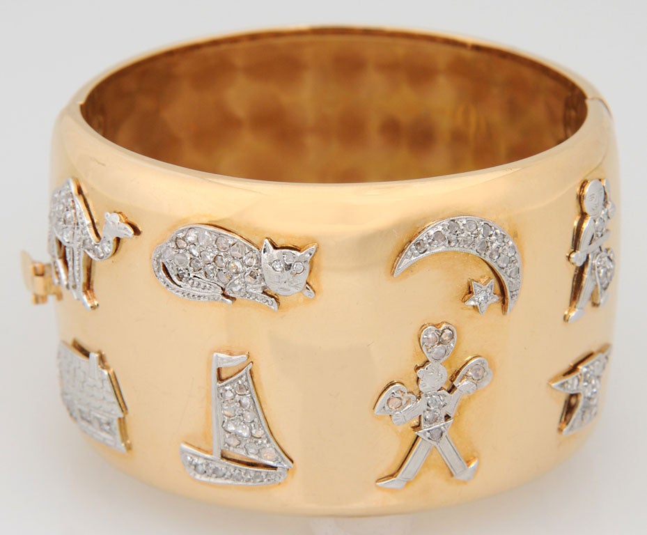 This is a wonderful marriage of 8 Deco platinum and diamond charms: Camel, Cat, Moon & Star, Musician, House, Boat, Anvil, and a Man holding Hearts (possibly a juggler).  These platinum charms were put into this 18k yellow gold bangle in the 40's.