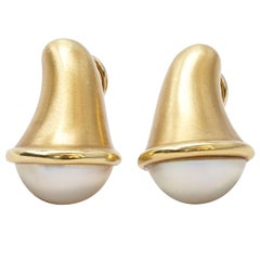 A pair of earclips with mabé pearl by Angela Cummings.