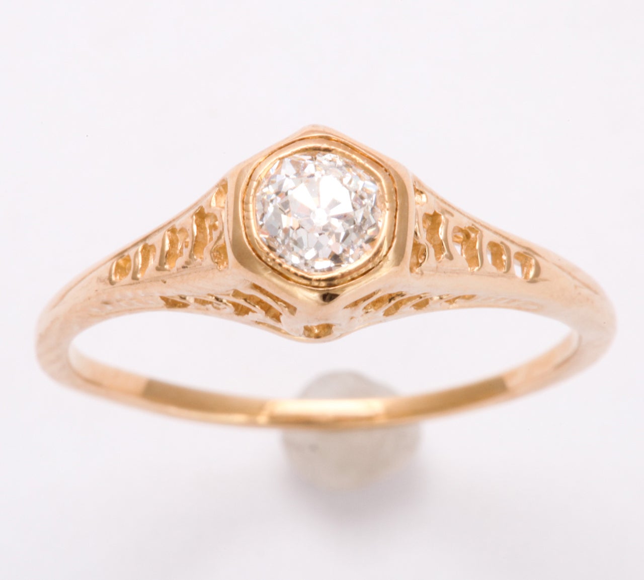 Enlarge the side view of this petite diamond ring and notice how the Art Deco structure raises the diamond to the eye. This graceful setting gives the .35pt diamond, majesty. The gallery below the gem was architected with cut out ovals and geometric