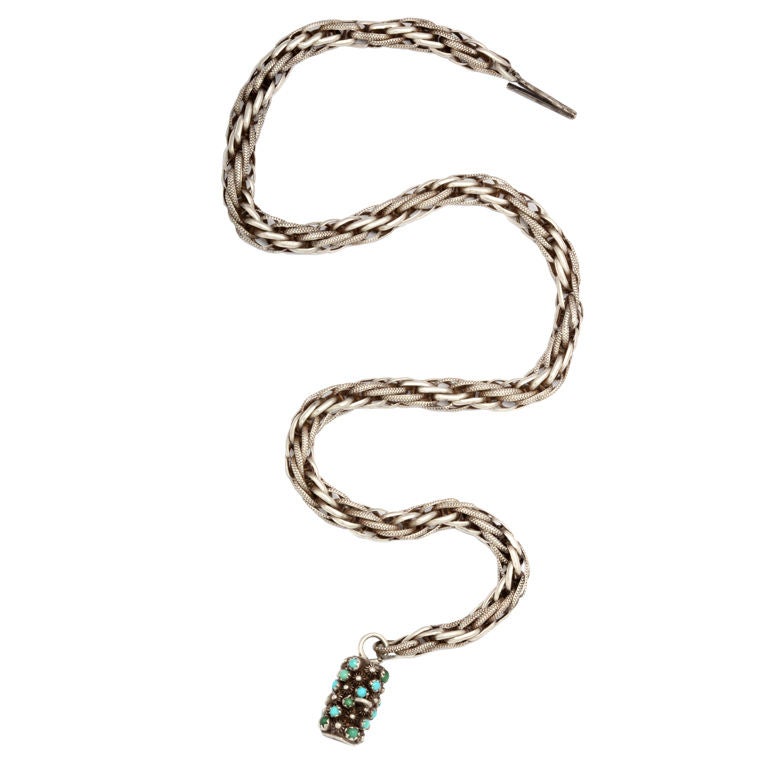 An eye catching hand made silver chain from Georgian England that is a significant piece of jewelry at the neck.  Interlocking links and braiding give texture and weight to the silver.  The lovely clasp is set with natural turquoise and can be worn