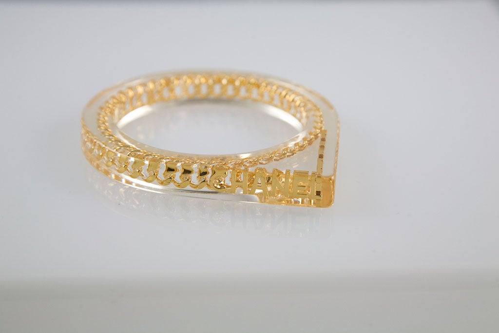 Stylish Lucite bangle bracelet from the House of Chanel.  Classic Chanel chain is embedded in lucite and ending in 