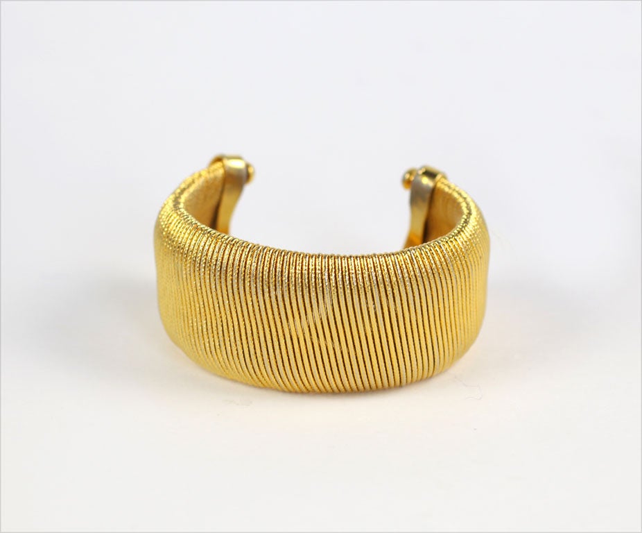 Goldtone cuff appears as if wrapped in gold metal string.