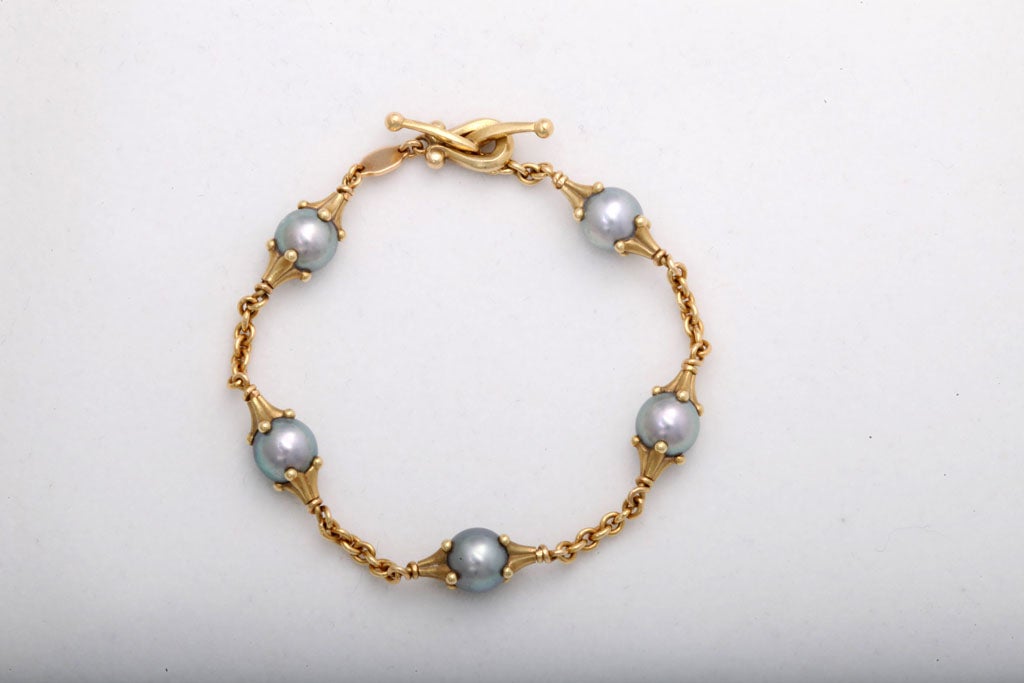Beautifully made bracelet with 5 lovely grey pearls between gold caps and chains.