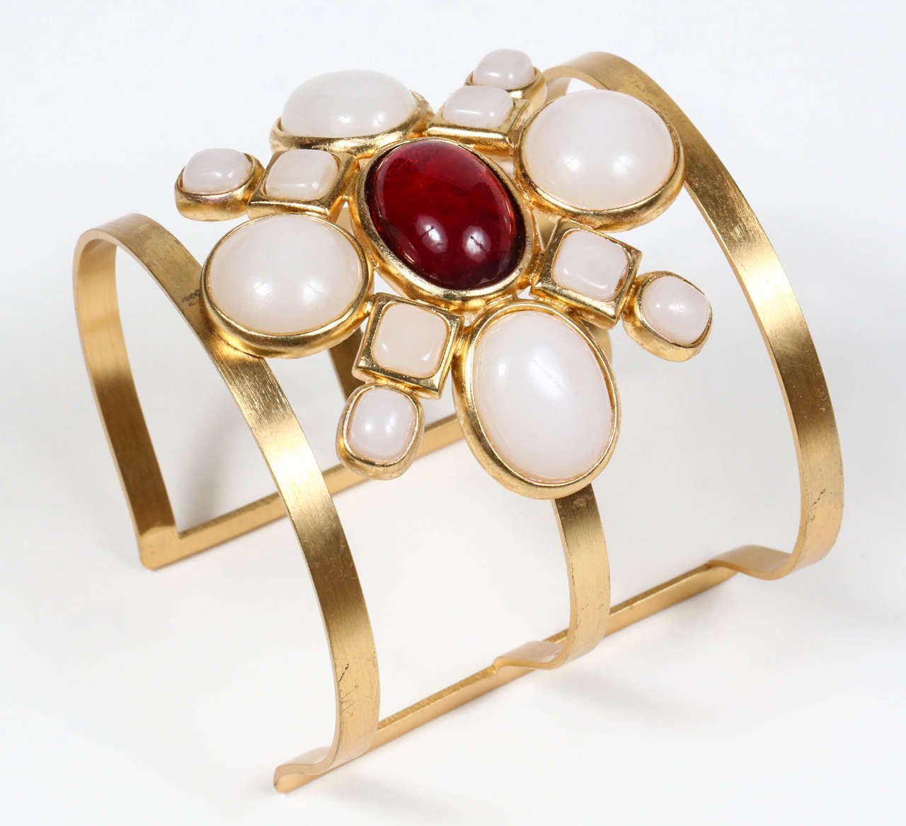 A striking gilt cuff featuring white and ruby red poured glass cabochons, designed to be worn on the upper arm. Marked on the band 