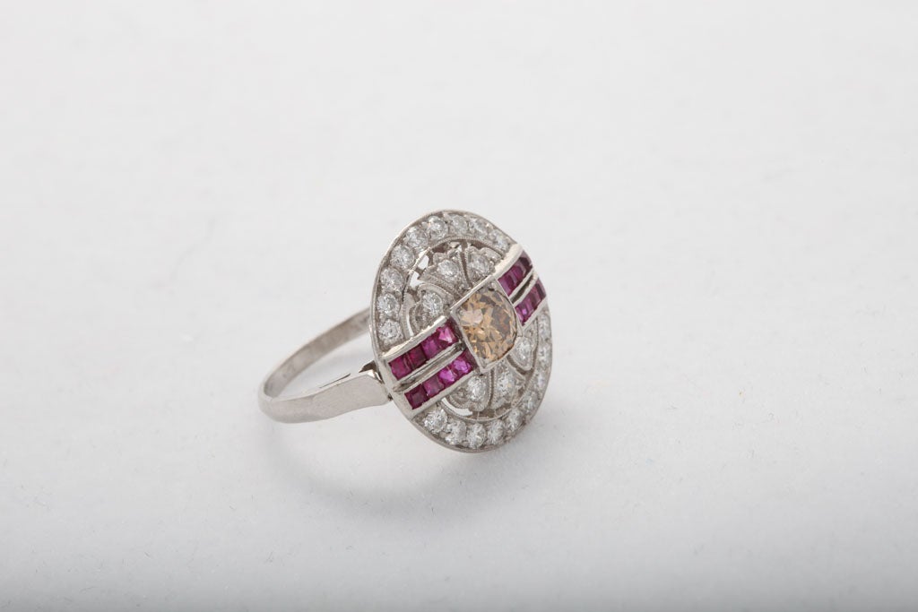 Chic Pinky ring set in Platinum with Center Cognac Diamond.  Fancy scroll work set with Full cut, clean & white Diamonds & accented by Channel cut French Rubies. Hot & intense!