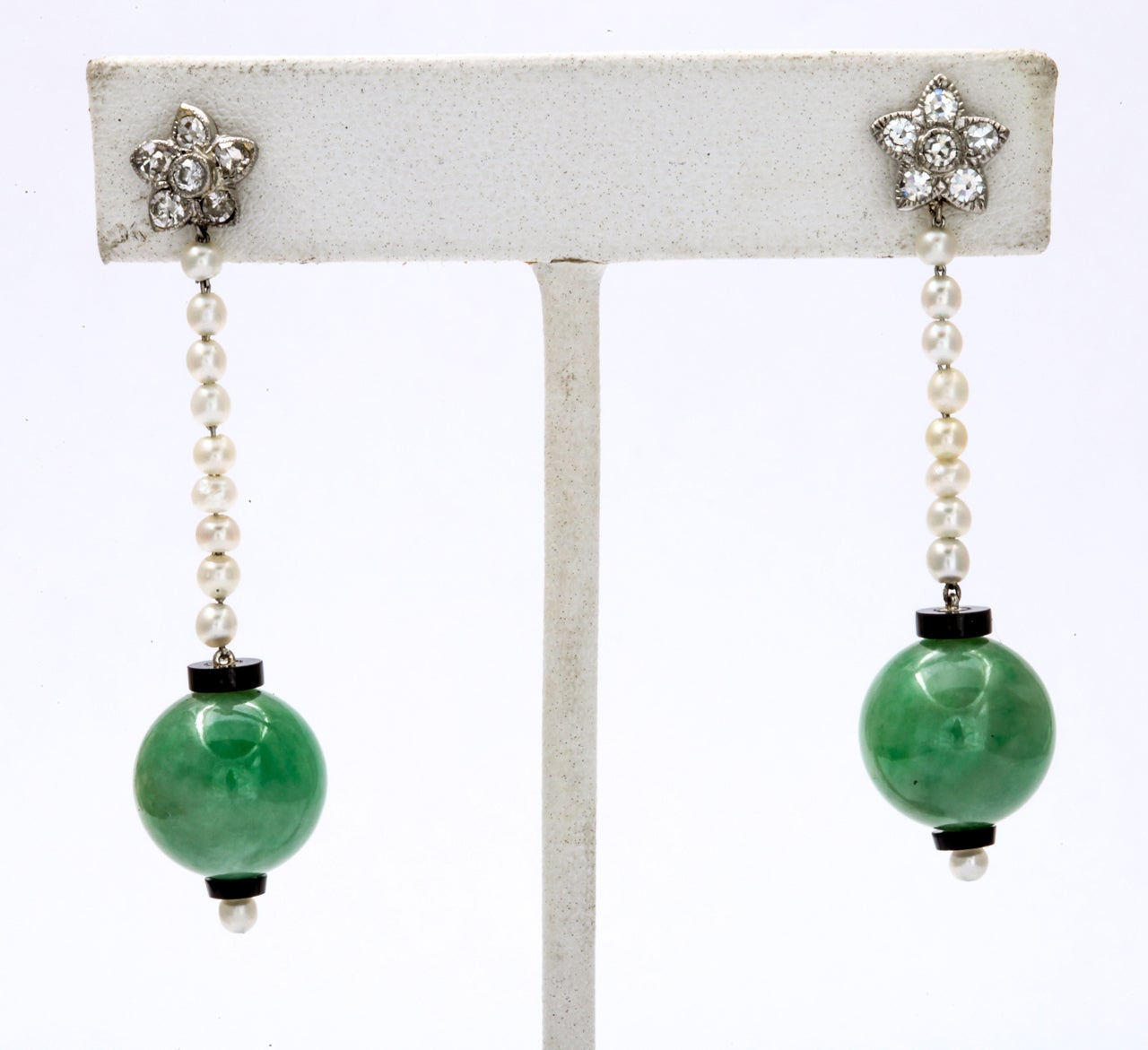 The jade orbs are a delicious, natural leaf green. The pearls are natural of glowing matching color. Petite diamond flowers cover the entrance to your ear which is and secured with posts of gold. Homage to Art Deco design is paid with the bit bit of