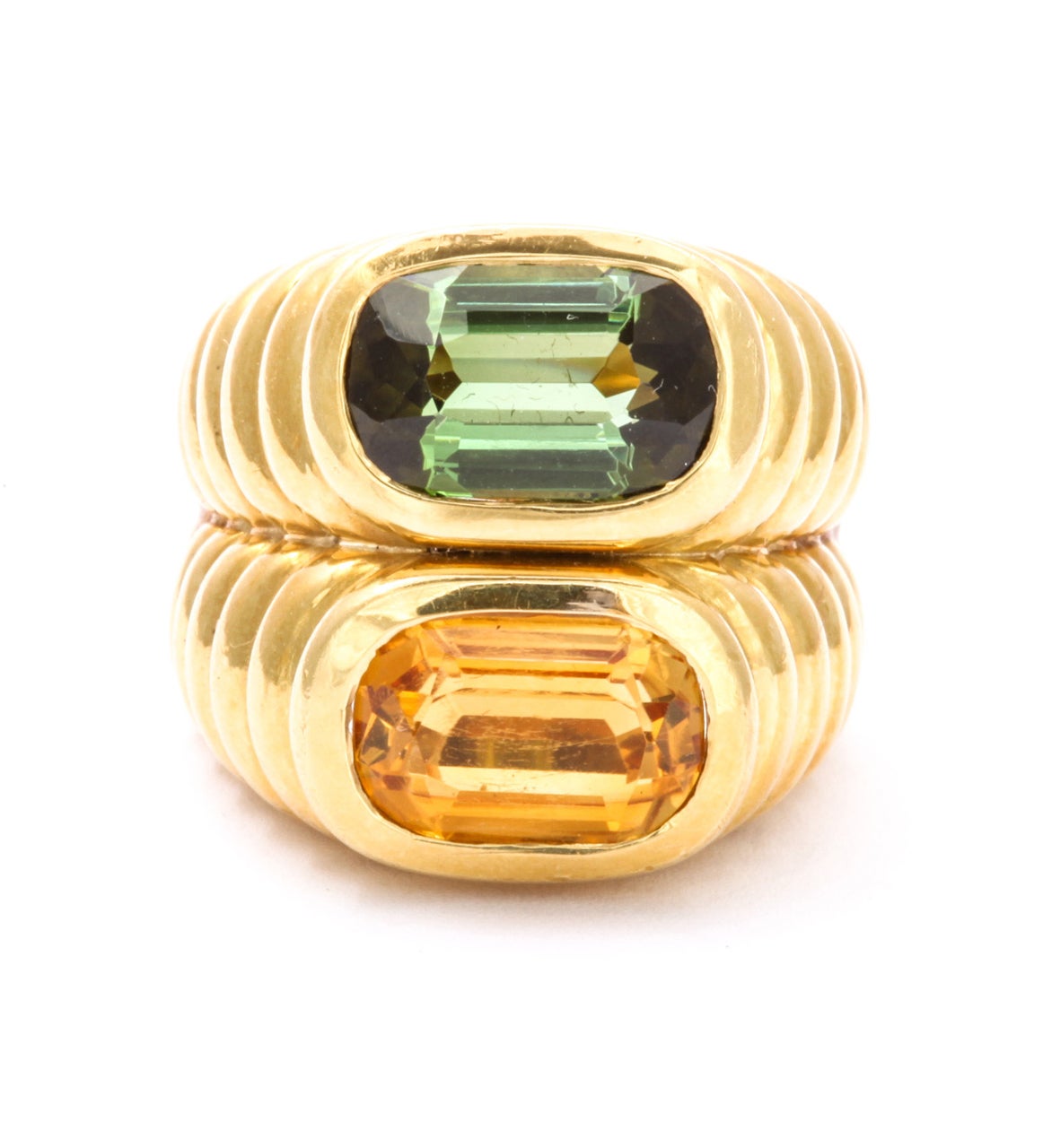 Chunky, deeply ridged concentric ovals rise from the finger to show the proud colors of green and gold set at their pinnacle. The stones, a tourmaline and a citrine are rounded rectangles, clear and color saturated. This ring, a dashing fashion