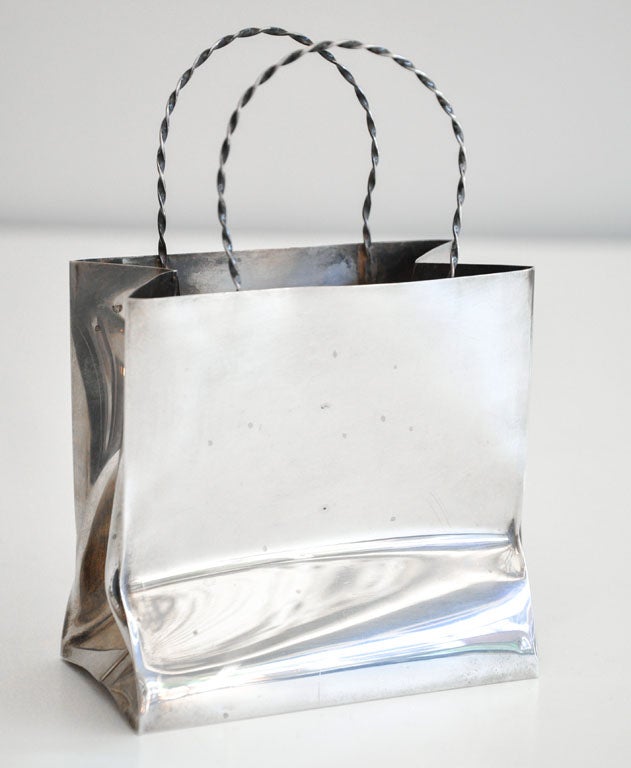 Whimsical hand-made sterling silver bag by Cartier designed 
to resemble a paper shopping bag with twisted cord handles. Signed.