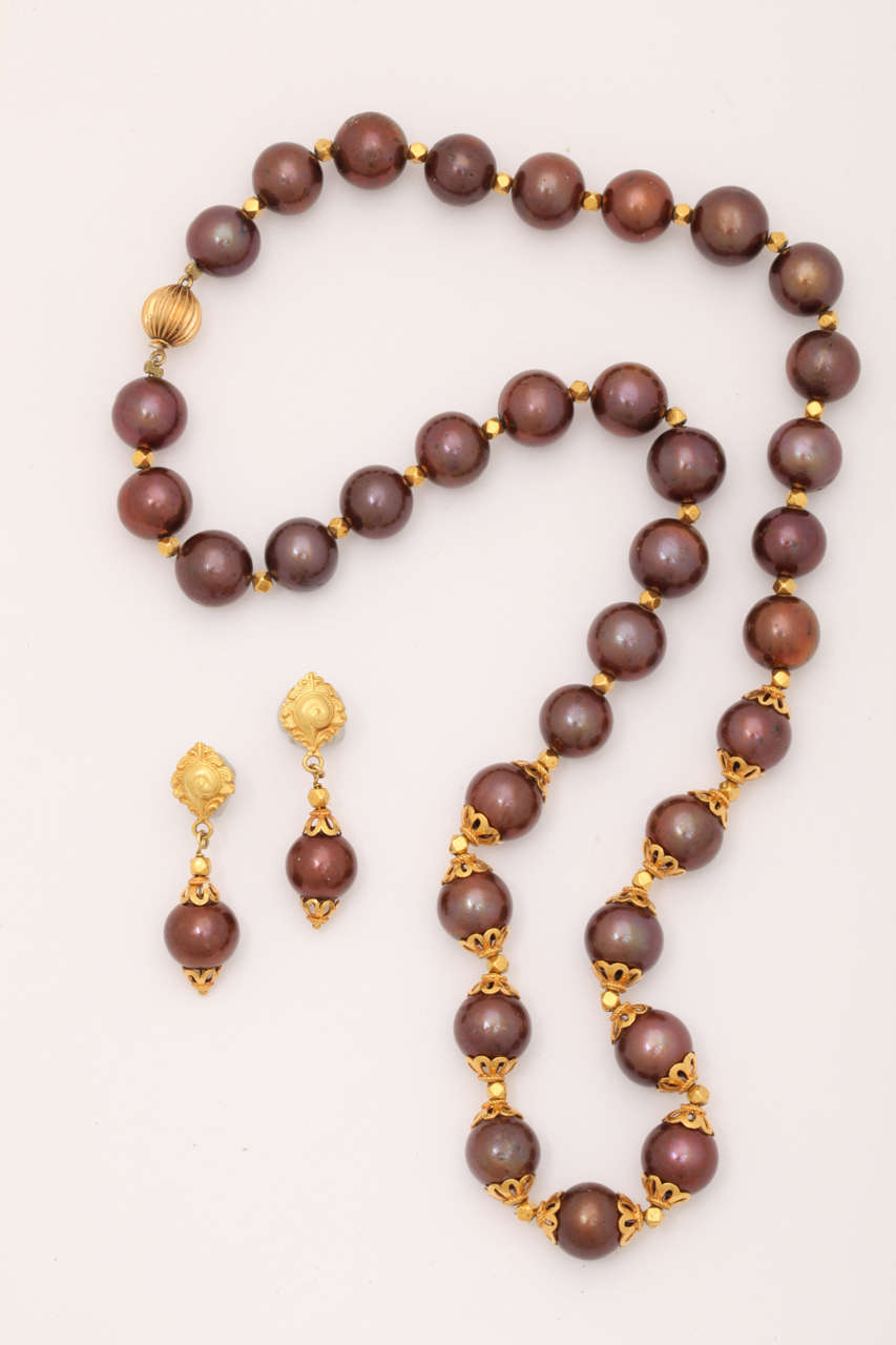 The necklace consists of 39,10-11 mm Chocolate fresh water pearls with 18 kt plated with 24 kt gold, beads and pearl caps. The total length  is 19 1/2 in.  The matching  post earrings are 1 1/2 in. long.The  rich combination of chocolate and high