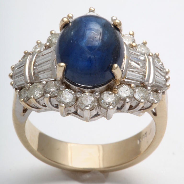 Center Cabochon Sapphire- prong set - surrounded by full clean & white Diamonds I flanked on either side by rows of Diamond Baguettes.  Shank is Yellow Gold.  Top is White Gold. Size 7.