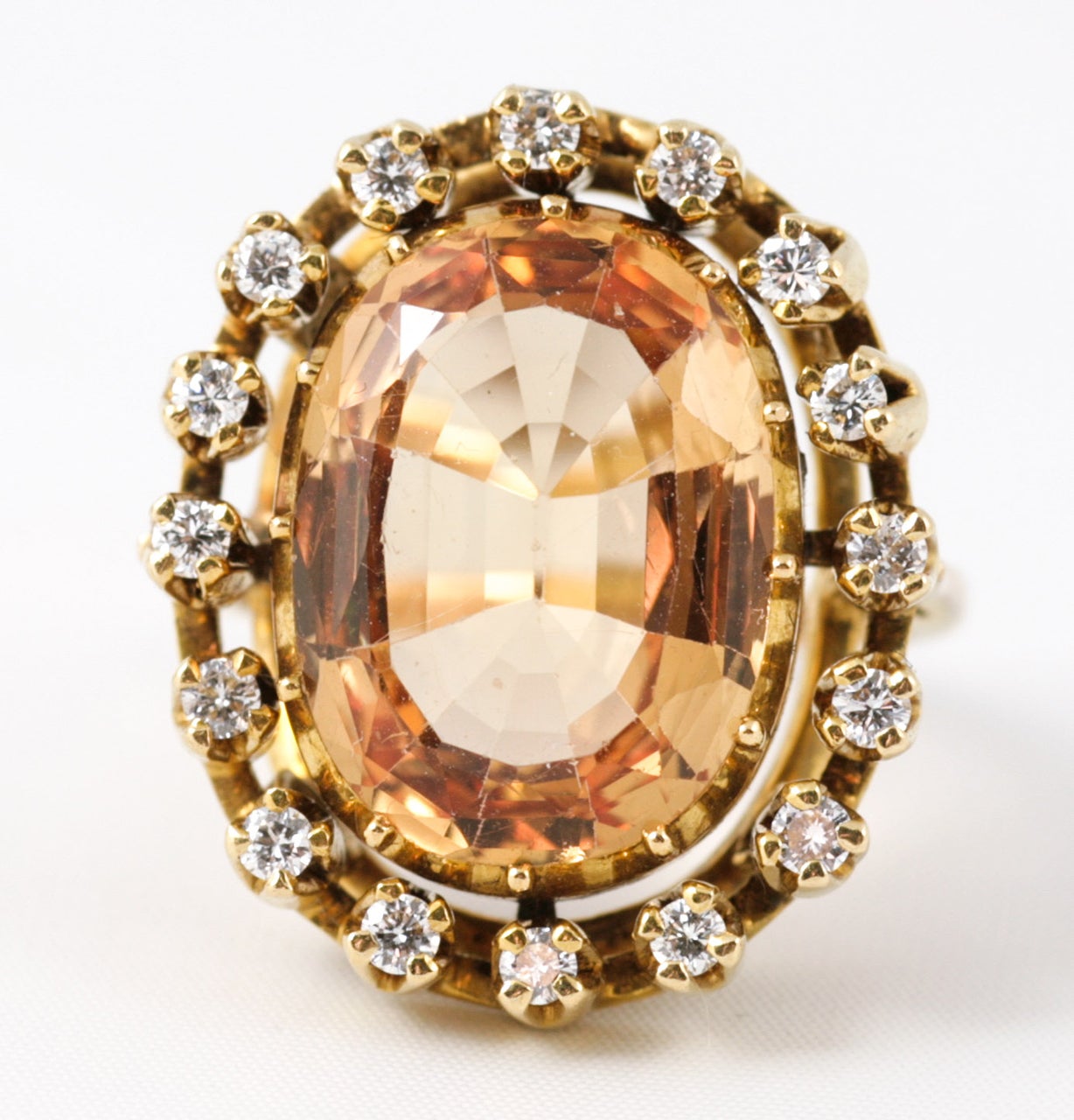 Oval Imperial Topaz surrounded by small Diamonds on a Gold shank
