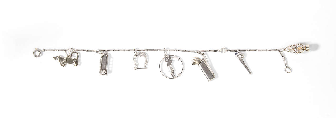 The bracelet decorated with seven charms, two signed Cartier.