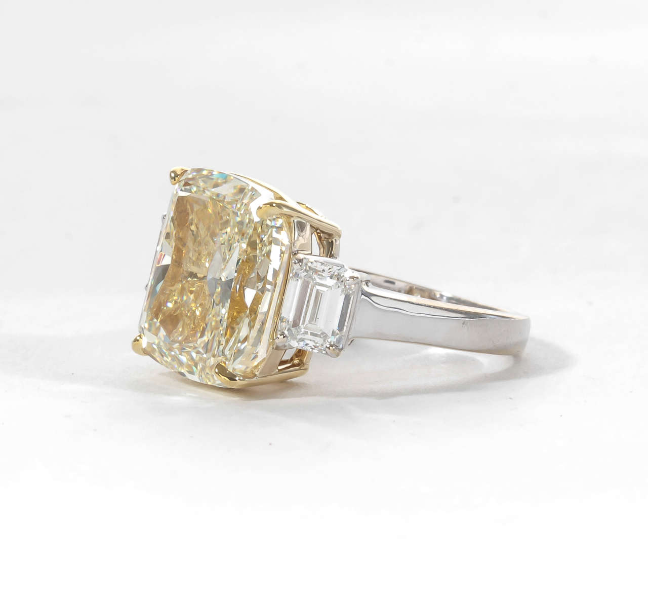 Impressive and brilliant 10.06 cushion cut Fancy Yellow, VS2 center diamond. 
1.41 carats of F color Vs clarity Emerald cut side diamonds all set in 18k gold.

This ring is a WOW!