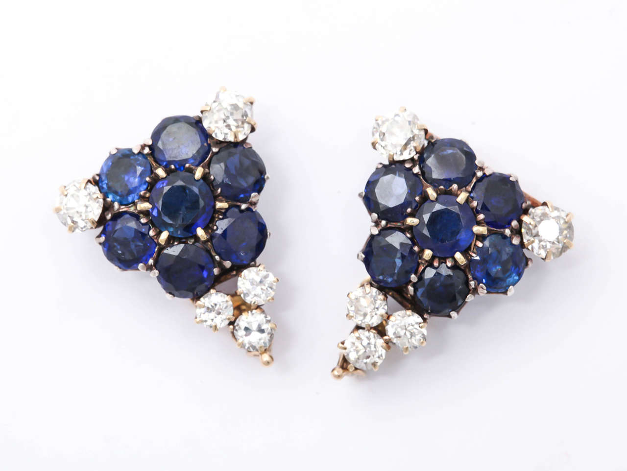 Pair of clips set in 18kt Yellow Gold & Platinum.  Beautiful intense Blue Sapphires making a floriform center & accented by full cut Old Mine Diamonds.
Ca. 1915-25.  
Can be separated & worn apart or as a clip.
