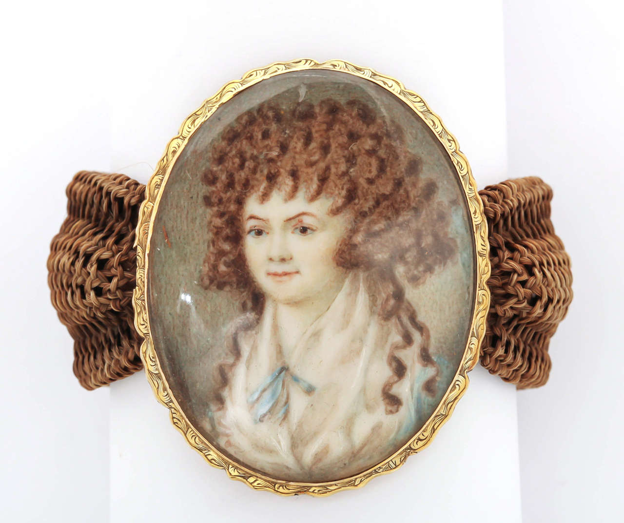 One of the most compelling 18th century is this young ginger haired girl with voluminous red curls. The parchment miniature is set in 18kt gold. Her features are fine, her eyes full of life and her smile innocent. Demurely attired as a young lady of