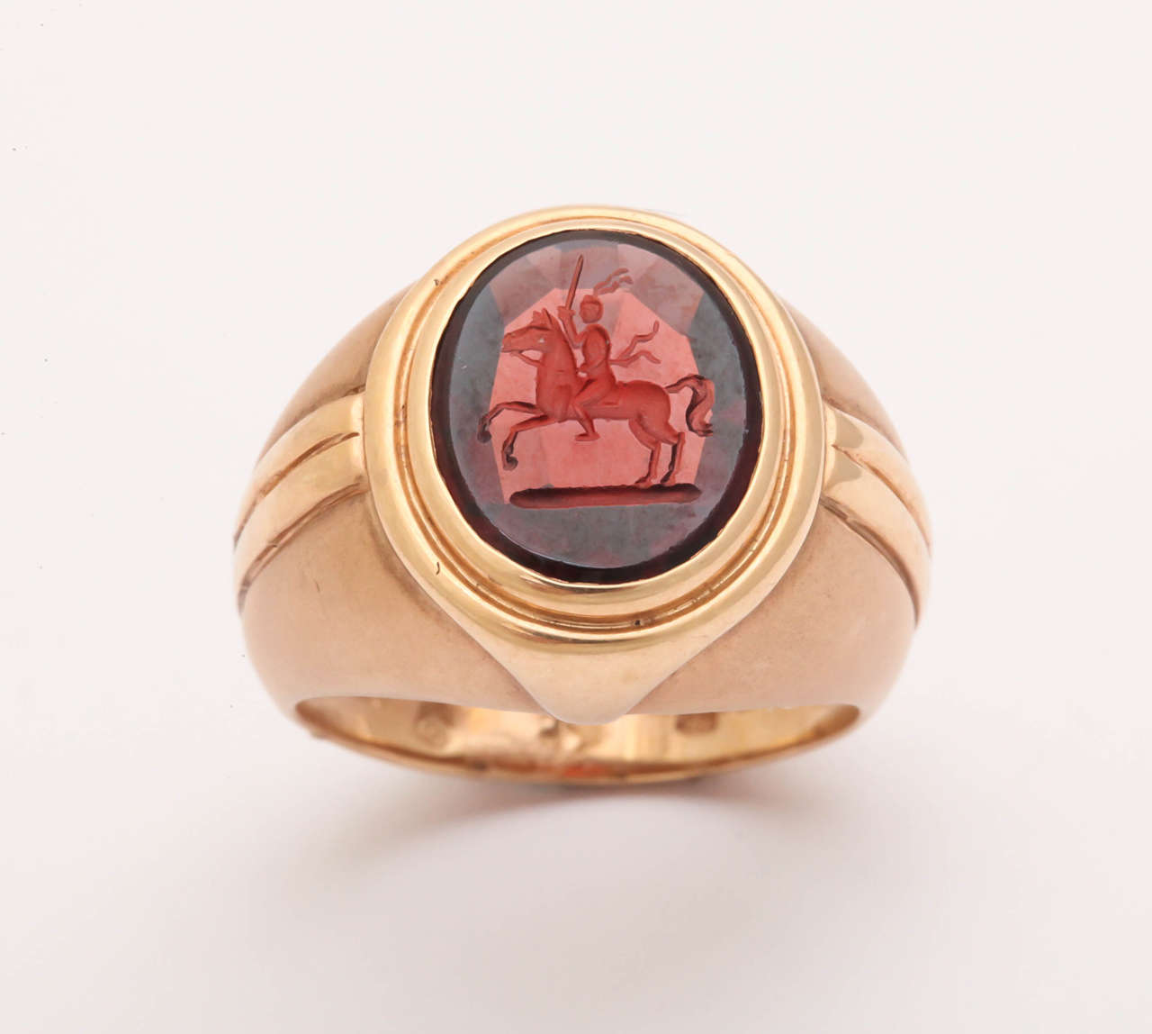 The design of this 18 kt rose gold ring has a Deco feel. The garnet intaglio was engraved by the expert stone cutters in Idar-Oberstein, Germany. The stone depicts a knight on horseback wielding a sword. This is a classic, elegant and impressive