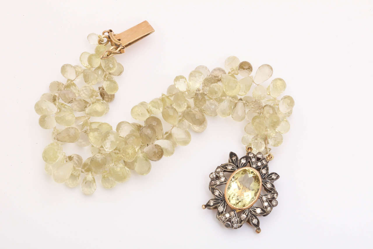 The silver and 14 kt gold vintage clasp is adorned with rosecut diamonds and a central lemon quartz faceted oval  gemstone 11mm by 15 mm in size.  the clasp also has 2 figure 8 safety clasps on either side for added security. The bright lemon quartz