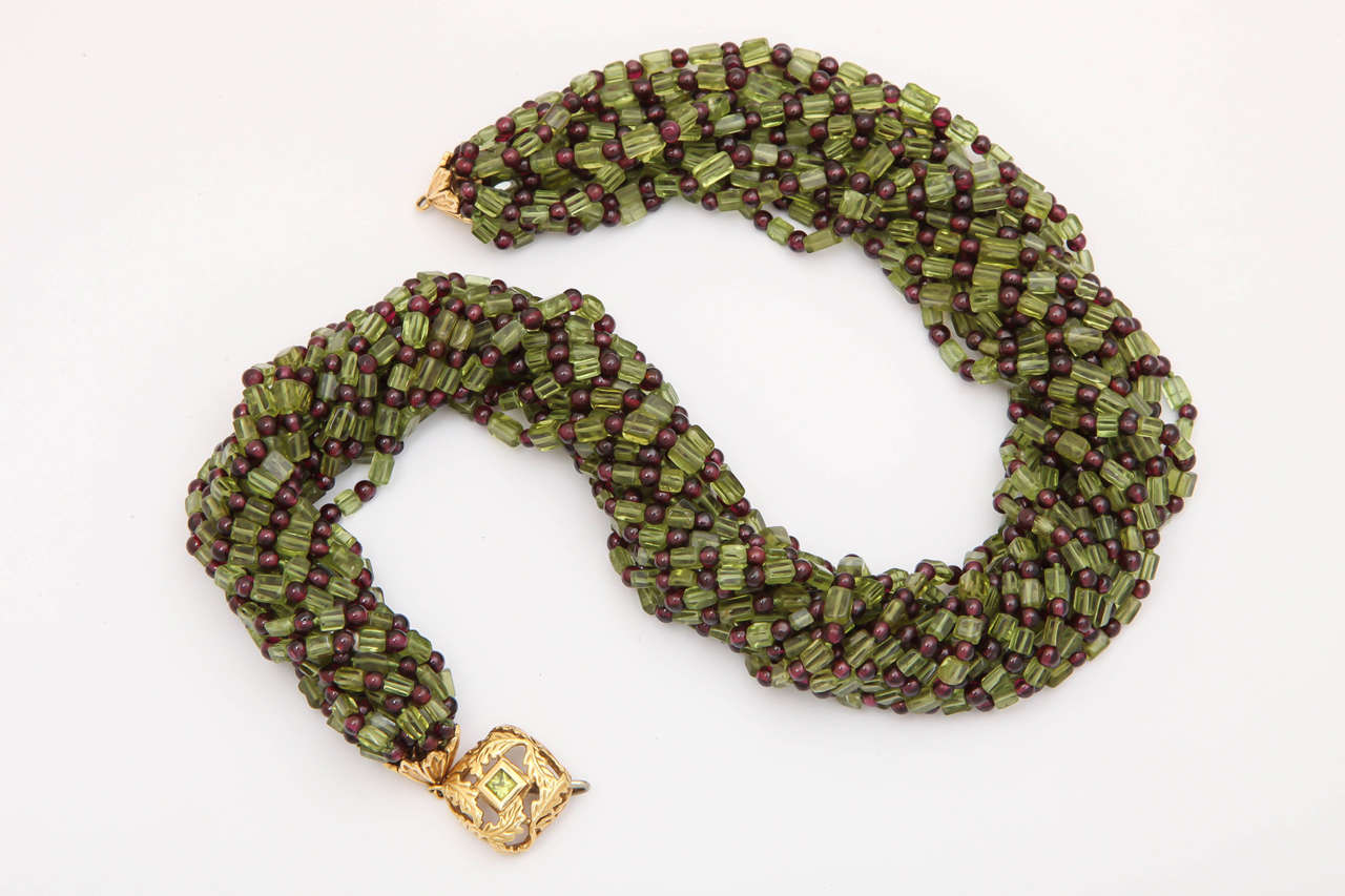 This stunning 15 stand necklace is made of rectangular peridot and 3 mm round garnet beads. The clasp is 18 kt yellow gold with a central square peridot, bezel set. It has a long goose neck hook for an easy yet secure closure and can be worn with