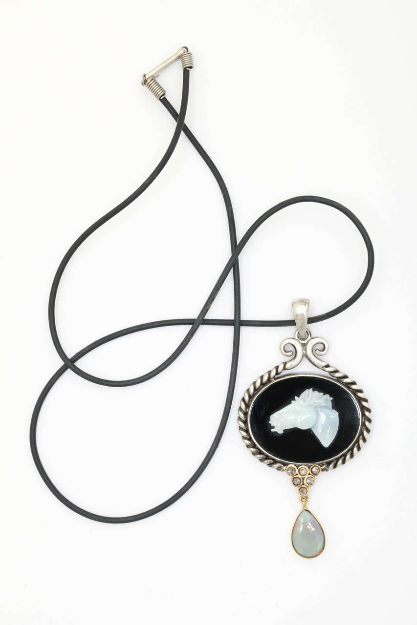 This handmade silver and 14 kt. pendant has an oval black onyx center sporting a carved opal horse head. There are 6 champagne rose cut diamonds at the bottom of the pendant finished by a pearl shaped natural opal. A timeless and elegant piece of