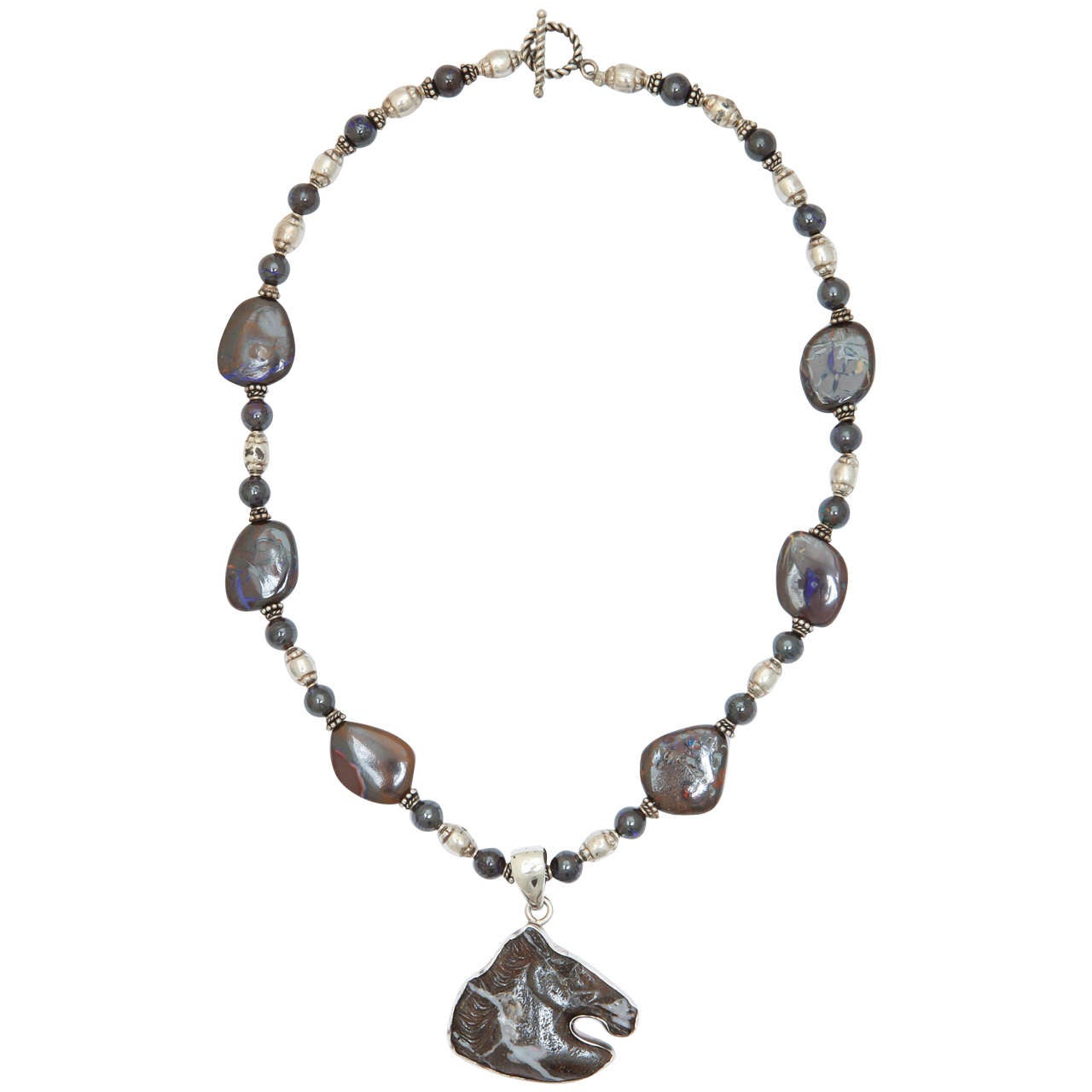 One of a kind necklace with a carved boulder opal horse head set in a silver bezel .The beads are flat nugget and round boulder opal with  silver beads in between, finished with a sterling toggle clasp. The total length of this powerful necklace is