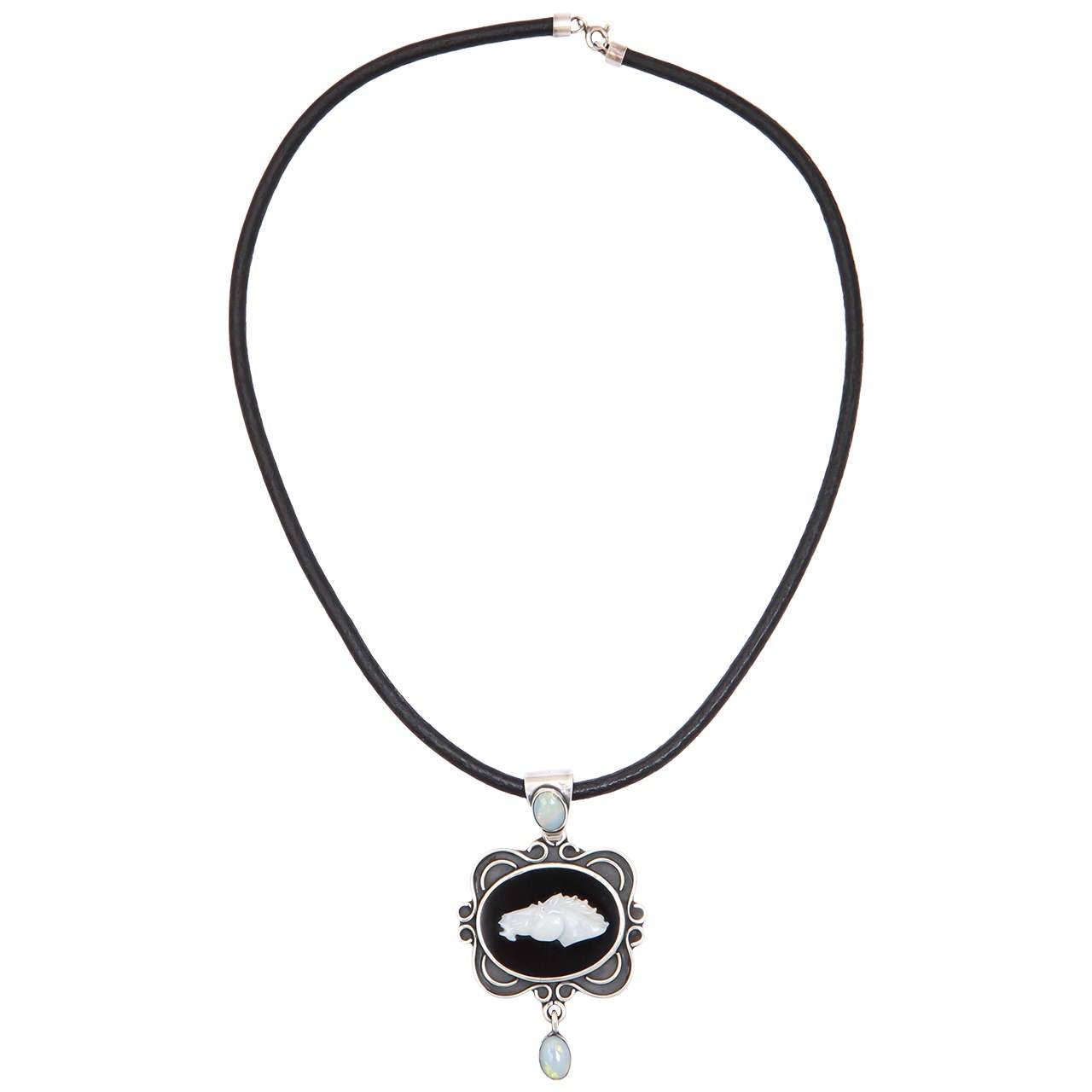 A wonderful necklace for the elegant equestrian. The mounting is hand made in sterling silver with a center of black onyx with a carved opal horsehead. There is a fine opal on the bale and also  as an articulated drop finishing the pendant. The
