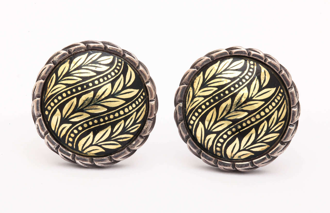 The black enamel disk center is 18 kt gold. The carved leaf bezel and back of the earrings are sterling silver. These earrings have a post and a clip for balance and stability. An elegant, classical earring for night or day.